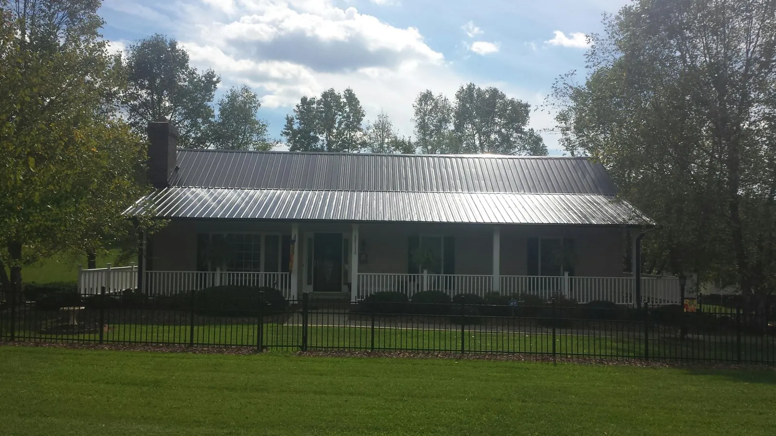 Gray metal roof on a brick ranch with a full width front porch — Gutter Guard Installation work by our crew in Ceres