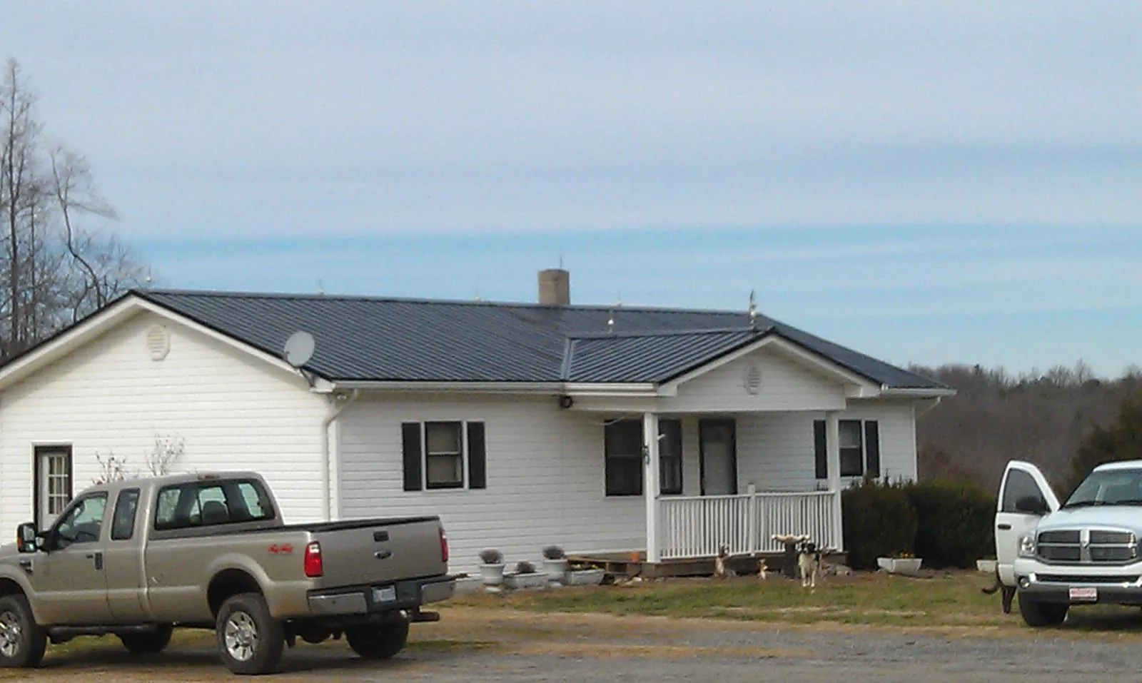 Finished dark metal roof on a white ranch home with work trucks parked in Ceres