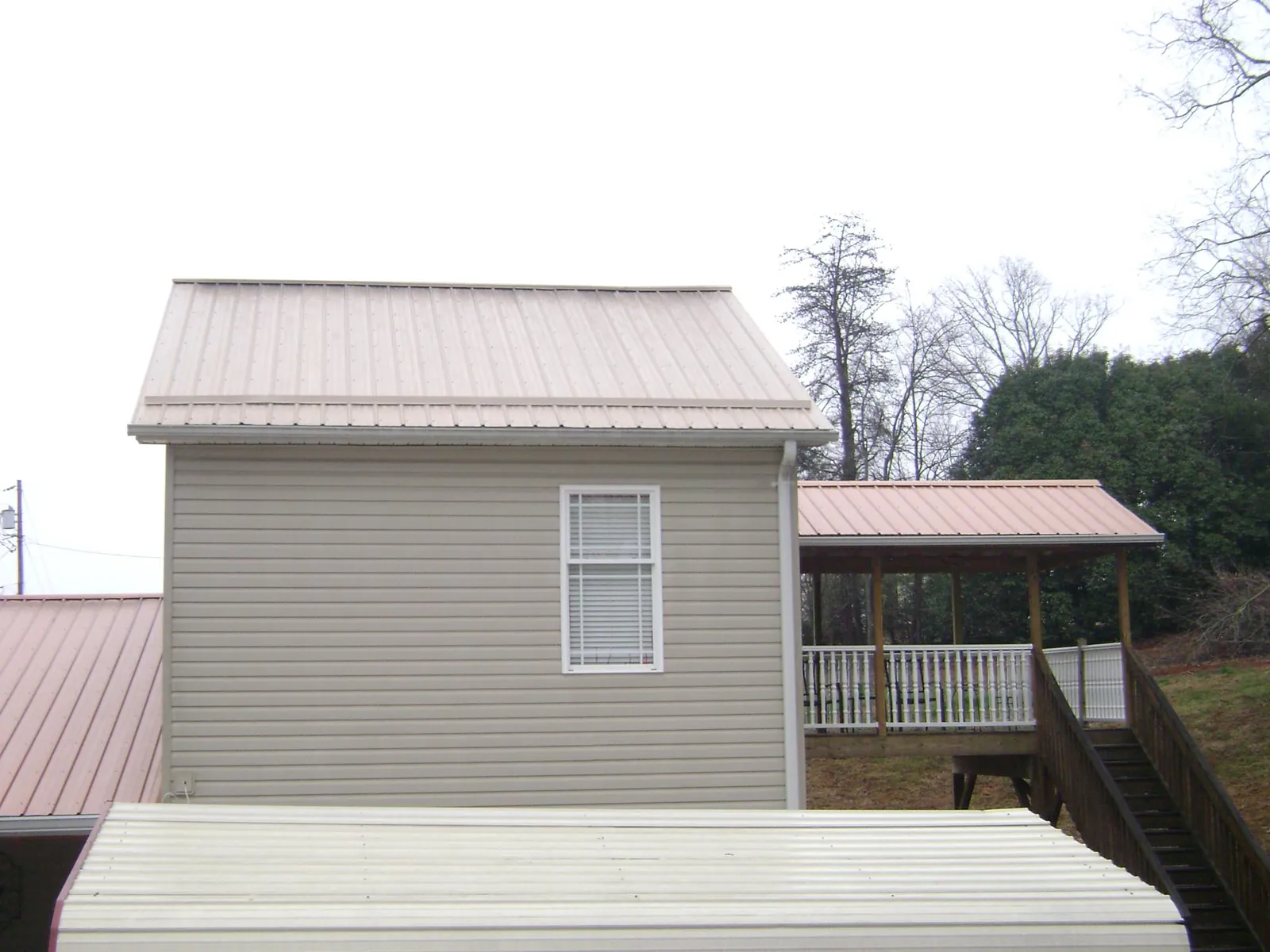 Tan metal roofs on a two story addition and attached porch, from a Roof Replacement job in Ceres